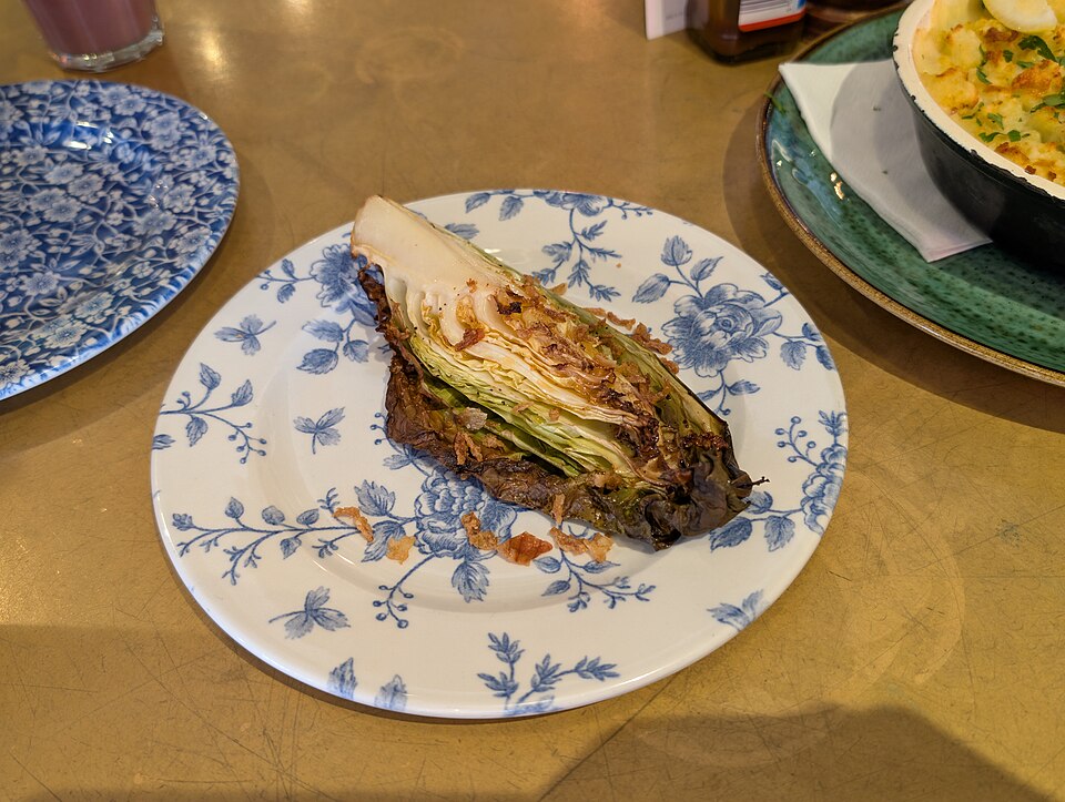 A deeply charred wedge of pointed cabbage served on a plate