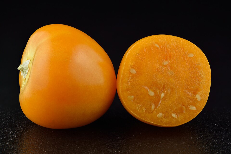 A jar of golden ground cherry jam with husks nearby