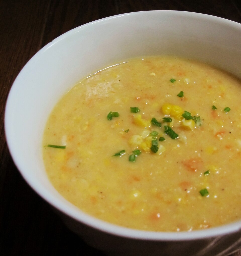 A bowl of golden corn chowder topped with chopped chives