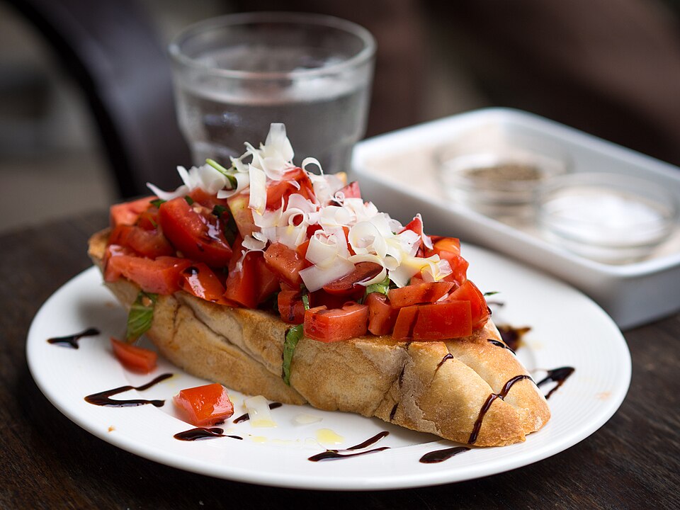 Slices of toasted bread topped with diced heirloom tomatoes and basil