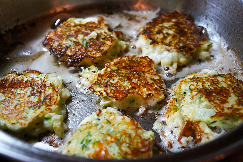 Golden zucchini and feta fritters piled on a plate